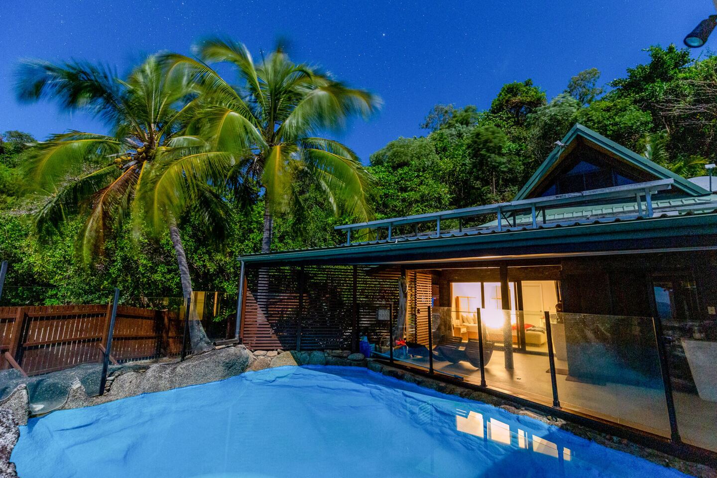 The retreat and its plunge pool among palms at dusk