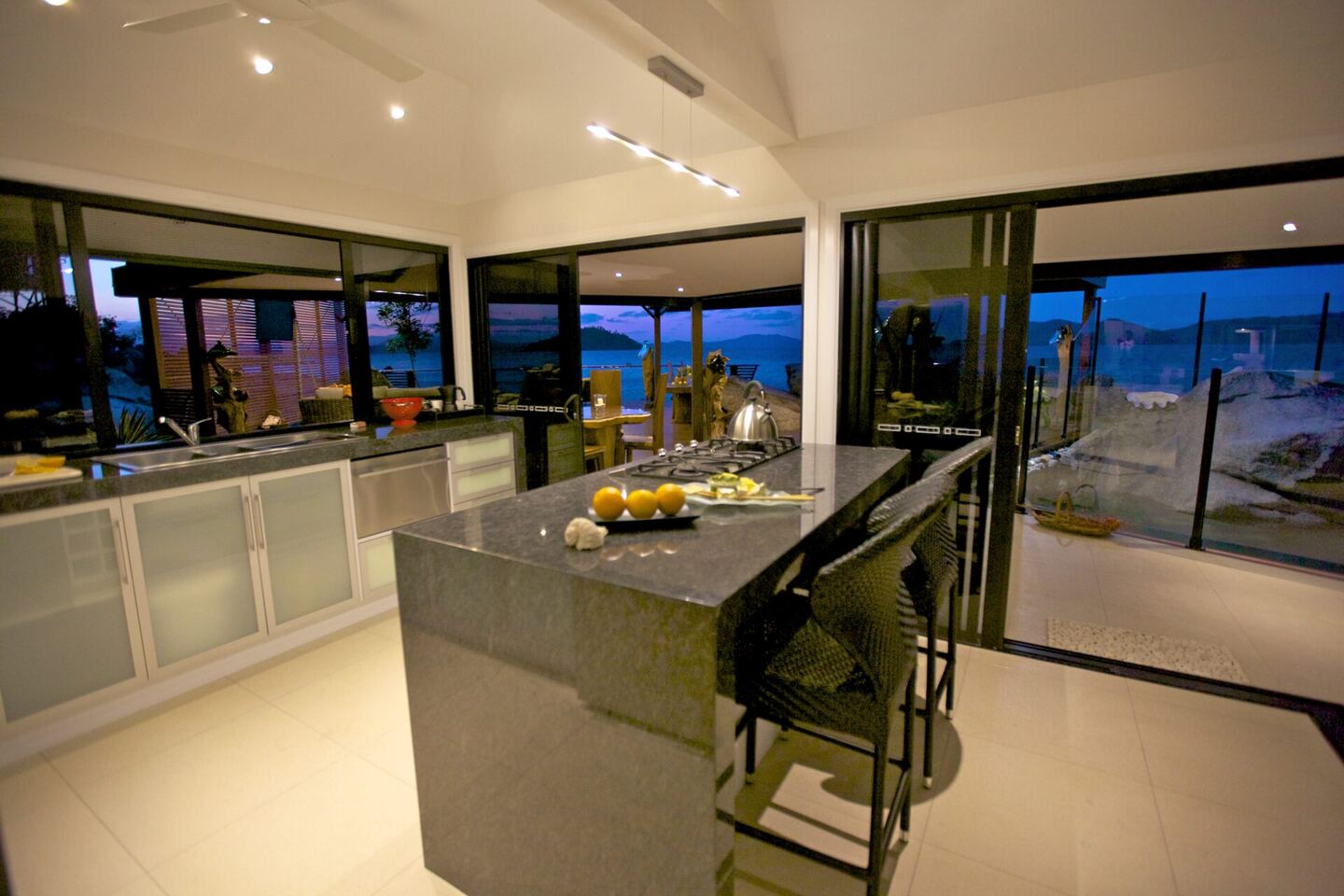 Kitchen with island bench and sea views through full-height windows