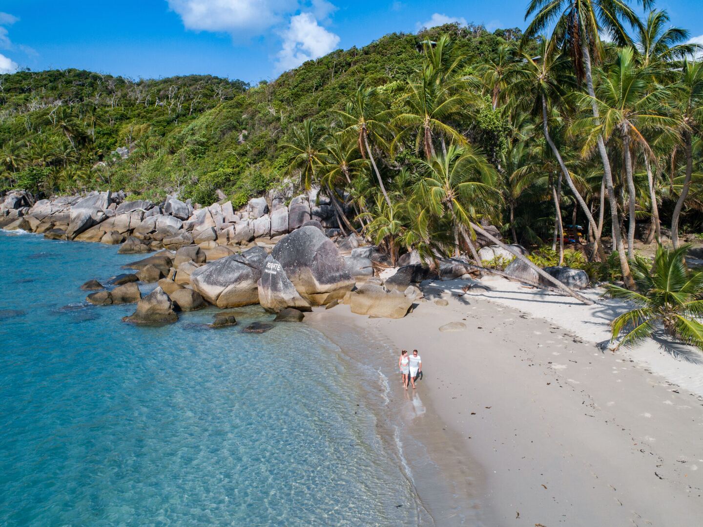 Aerial view of the beach and headland with a guest walking the shoreline